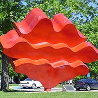 The red steel sculpture titled Waves is located outside near Memorial Library on the Minnesota State Mankato mall