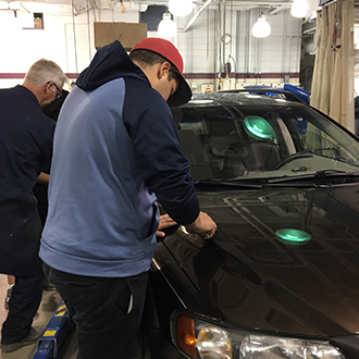ETS Student working with a car in the Hennepin Technical College Auto Shop