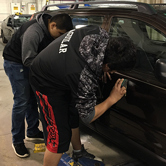 Students inspecting a vehicle in the Hennepin Technical College Auto Shop