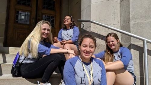 Four female ETS students posing on stairs outside a building on the campus of St Scholastica