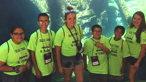 ETS students posing in front of a large aquarium at the MN Zoom