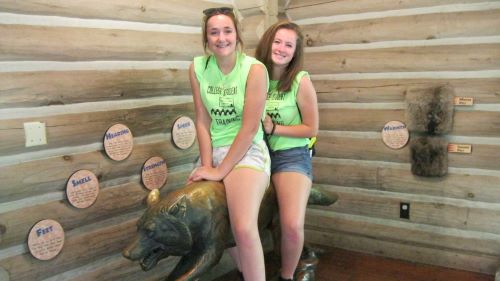 two female ETS students posing on a statue of a wolf at the minnesota zoo