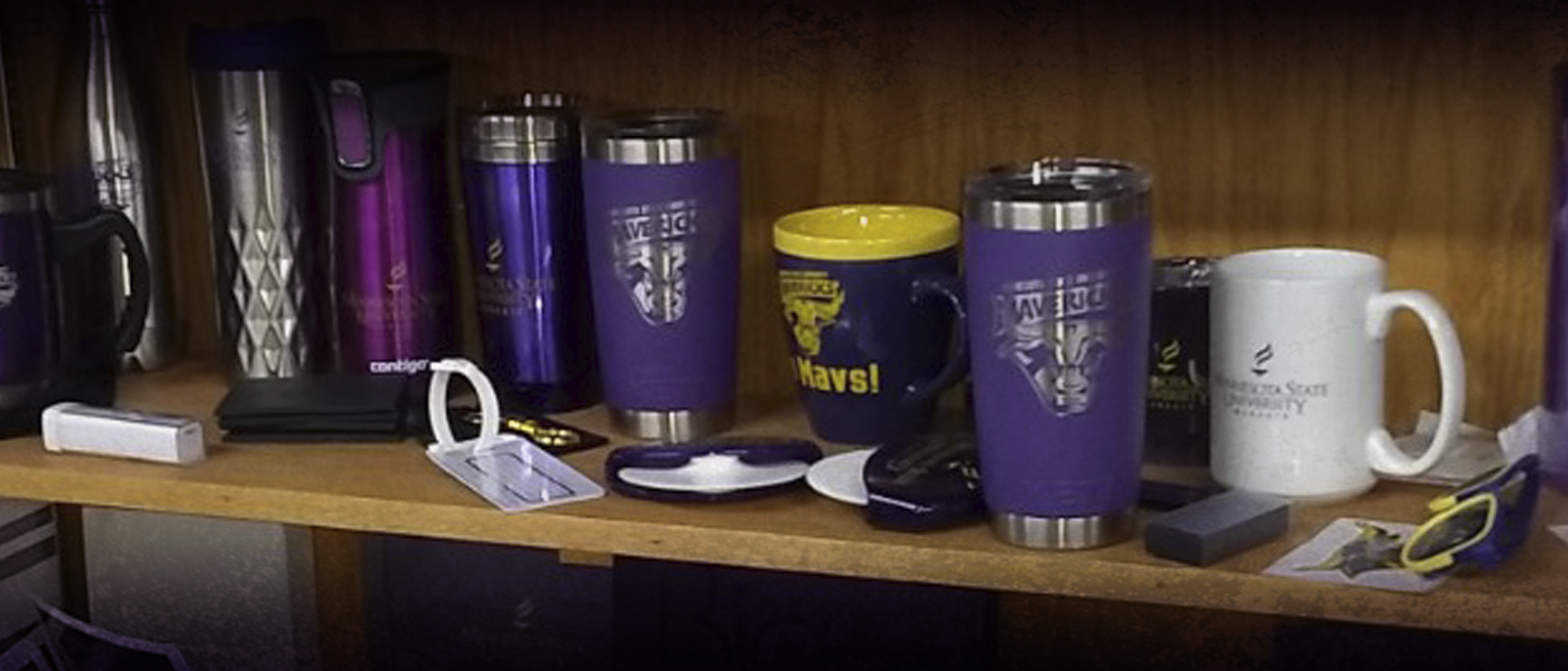 a group of purple mugs and a yellow mug on a shelf