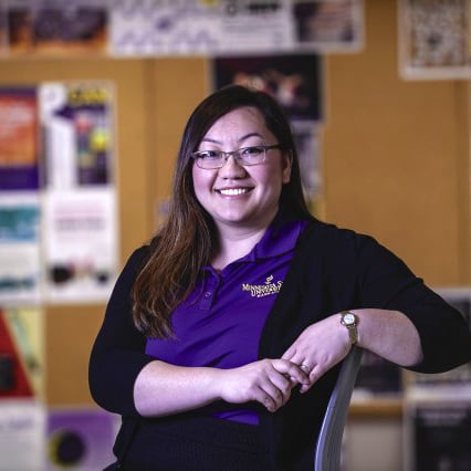 A Student Financial Services employee posing on a chair and smiling