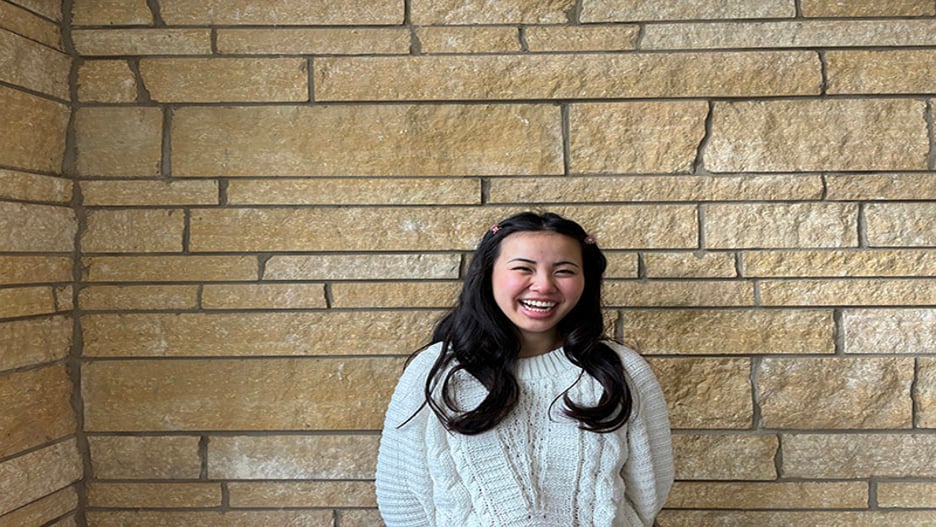a person smiling in front of a brick wall