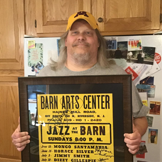 John Aho holding a framed Jazz at the Barn poster