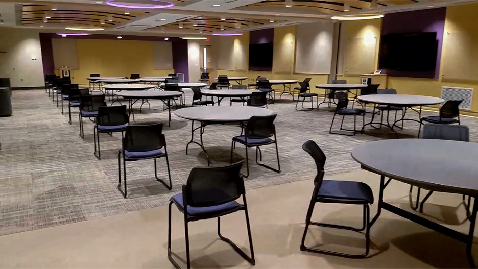 Overview of a meeting room with round tables and a large monitor on the wall