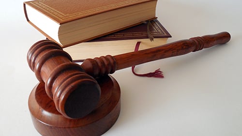 A wooden gavel and plate with law books on a table