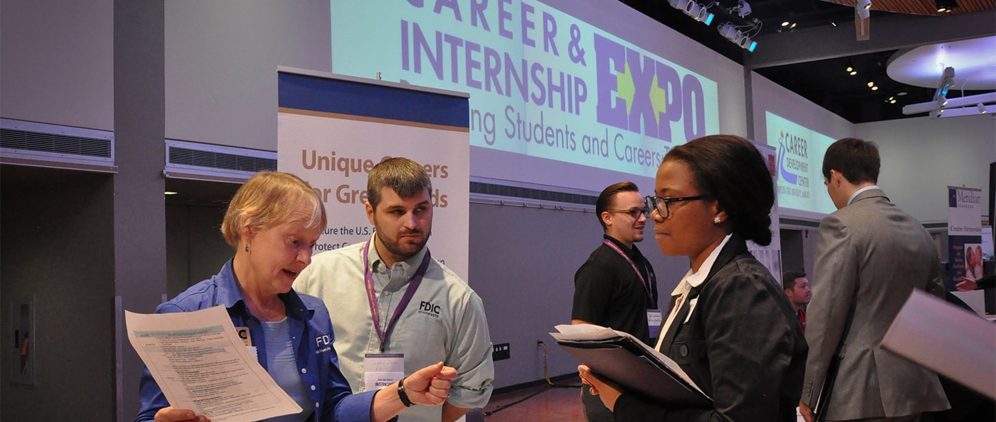Recuiter talking with a colored student about her resume in the Minnesota State University Career Expo