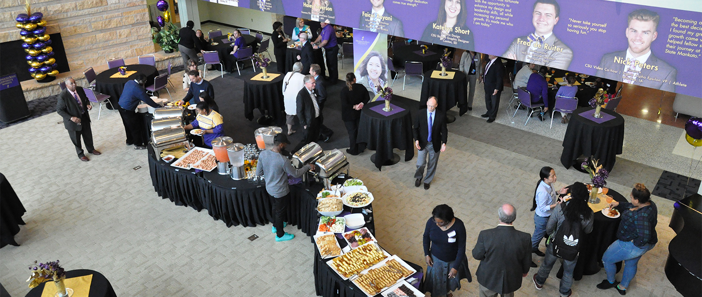 Students and faculty members having discussion in smaller groups and enjoying foods being served in the Hearth Lounge