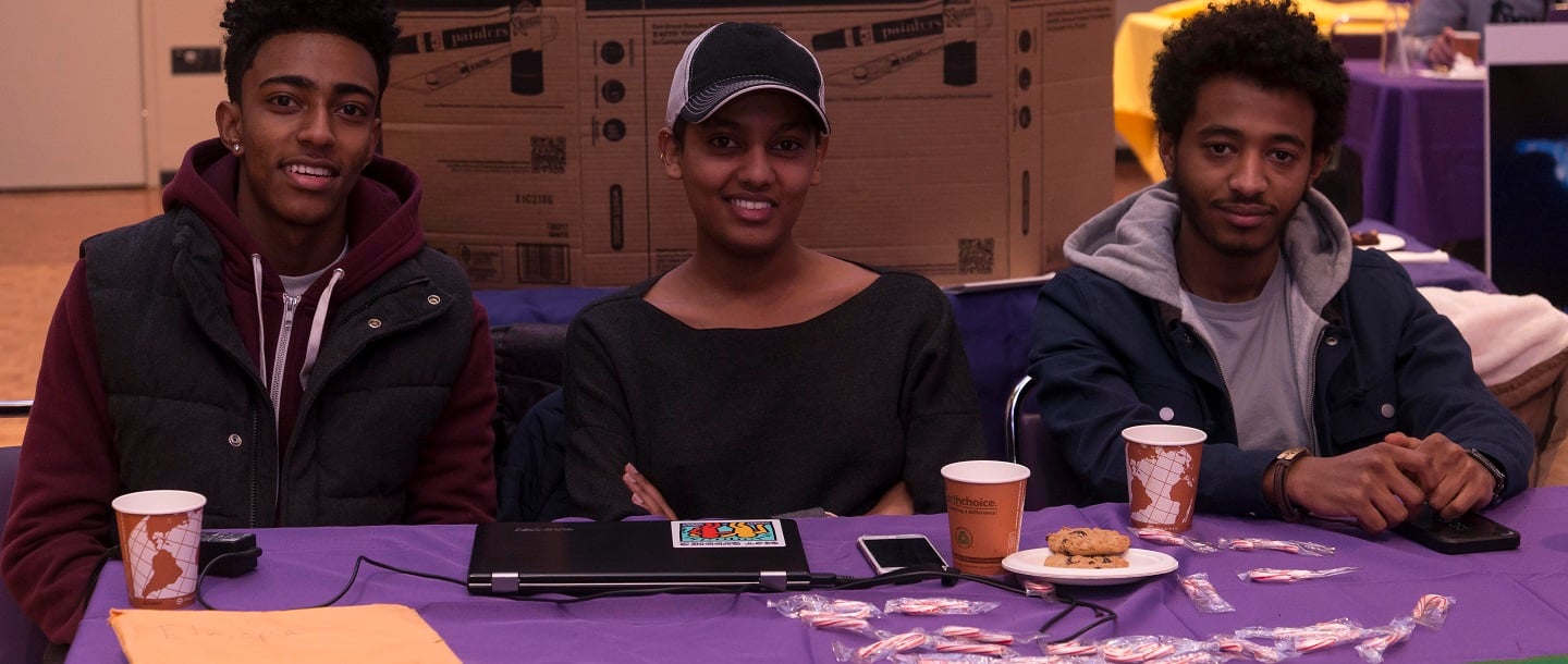 Picture of three students (two men, one woman) at a table for a resource fair