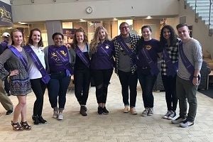 Members of the Homecoming Royalty Court of 2017 posing for a photo on campus wearing purple sashes