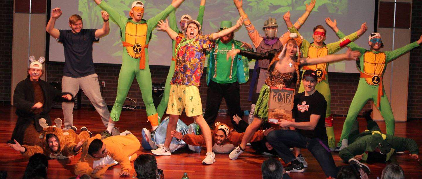 Students in different costumes dancing and singing on stage