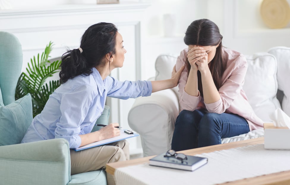 a person holding her face to her crying friend