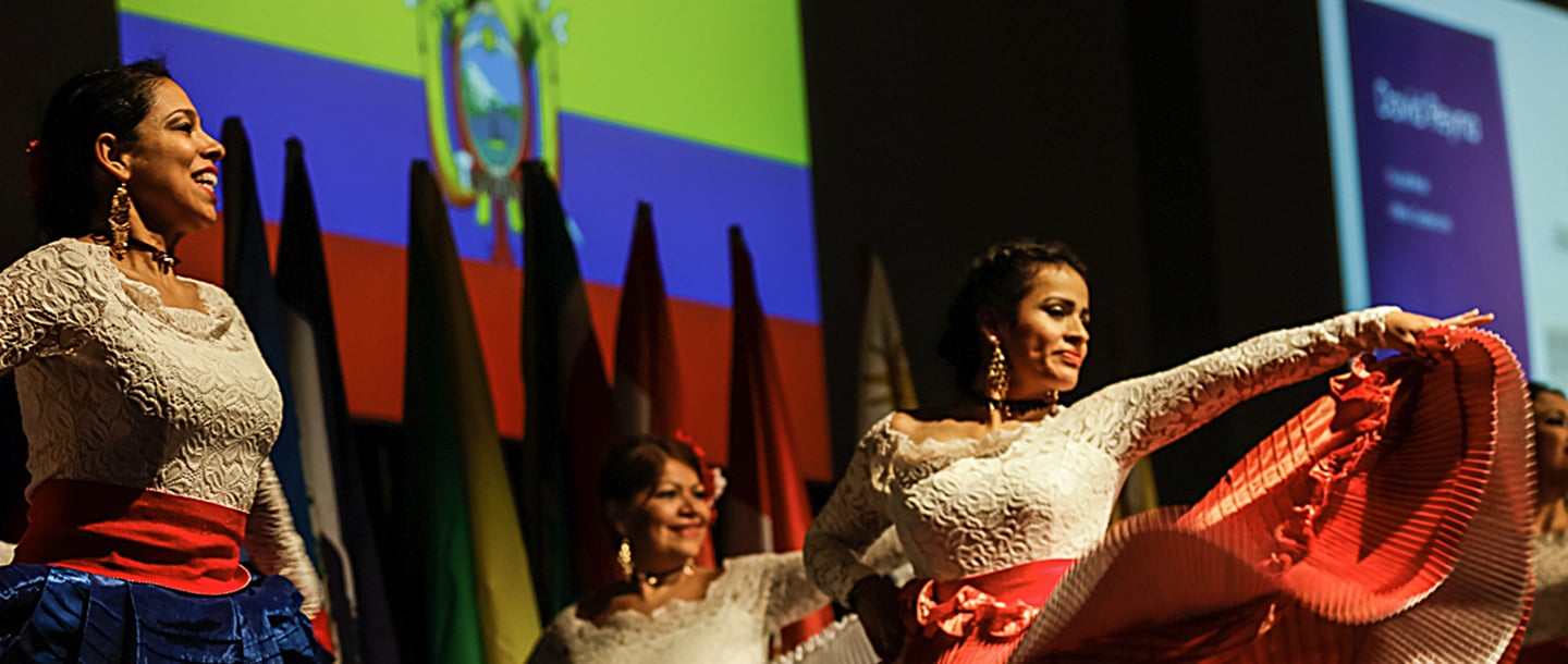 three Latino students dancing in white traditional dresses at Latino night