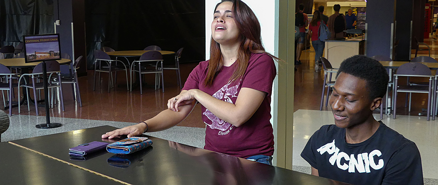 A student singing while another student is playing the piano in the lower level of the CSU