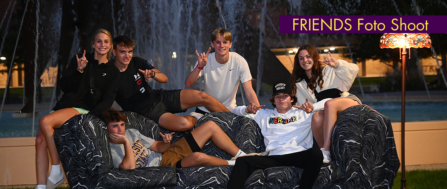 Students sitting on a couch outside on campus for the 'friends foto shoot' showing the 'horns up' Maverick sign