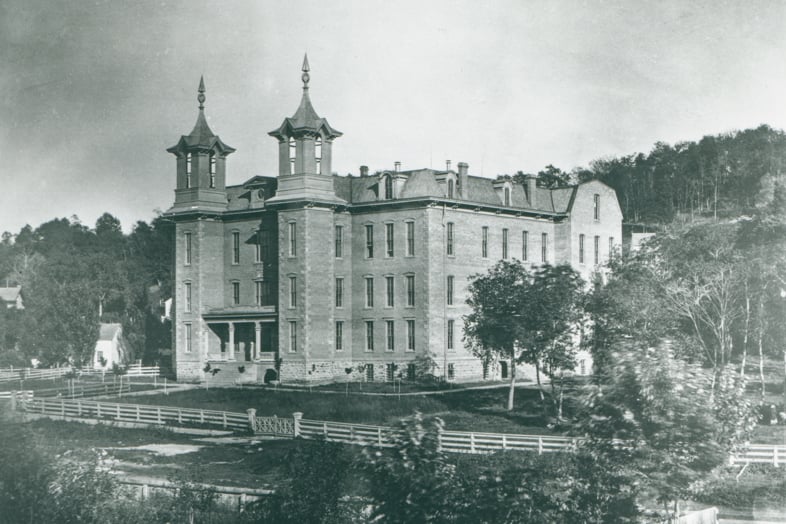 a large brick building with a fence and trees