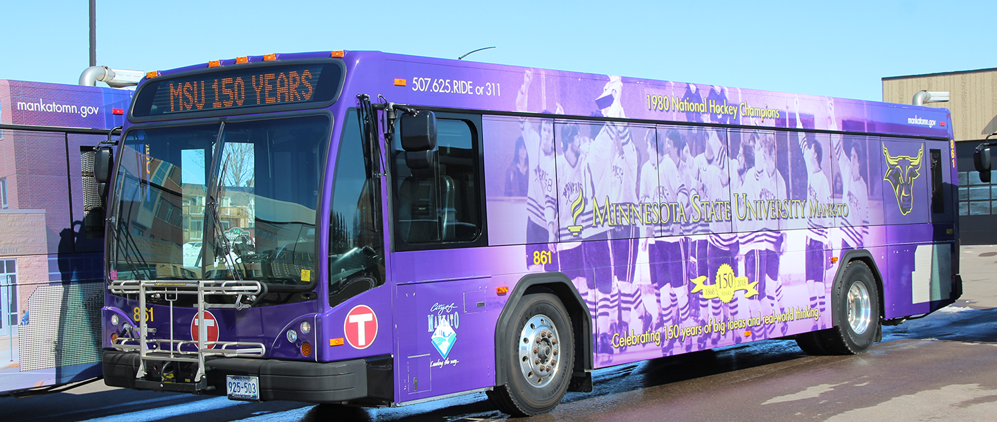 City of Mankato bus with the Minnesota State Mankato 150th anniversary logo wrap that says "1980 National Hockey Champions" at the top and "Celebrating 150 years of big ideas and real-world thinking" at the bottom