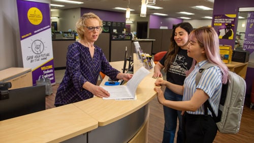 Students and staff member at the front desk inside the career development center