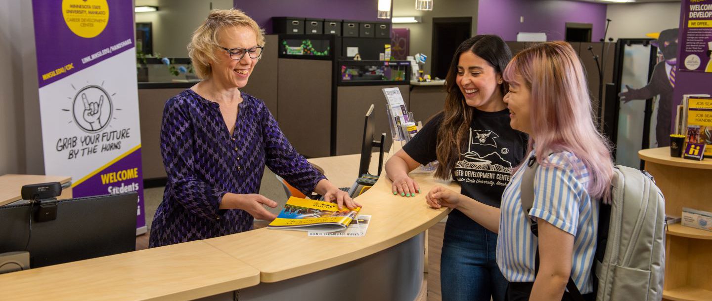 Students and staff member at the front desk inside the career development center