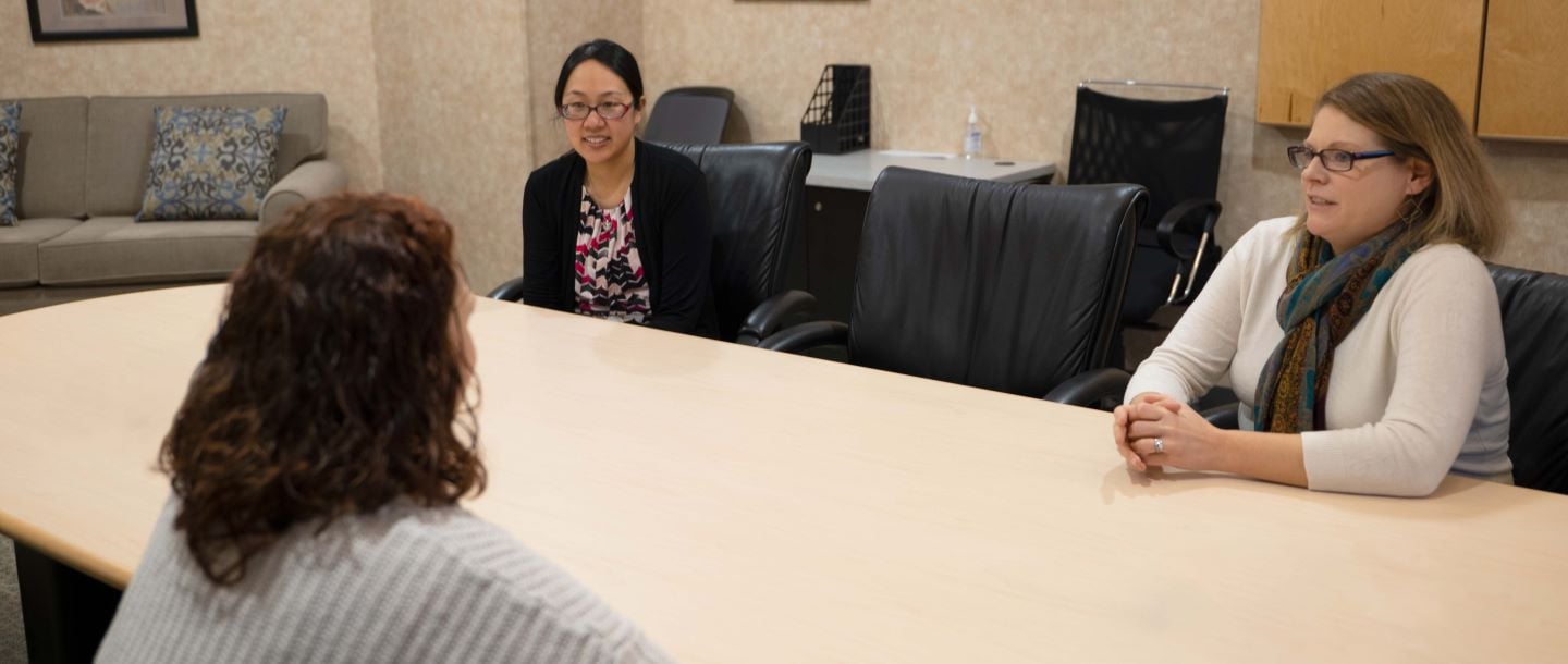 Three staff members sitting at a table in a meeting room having a discussion
