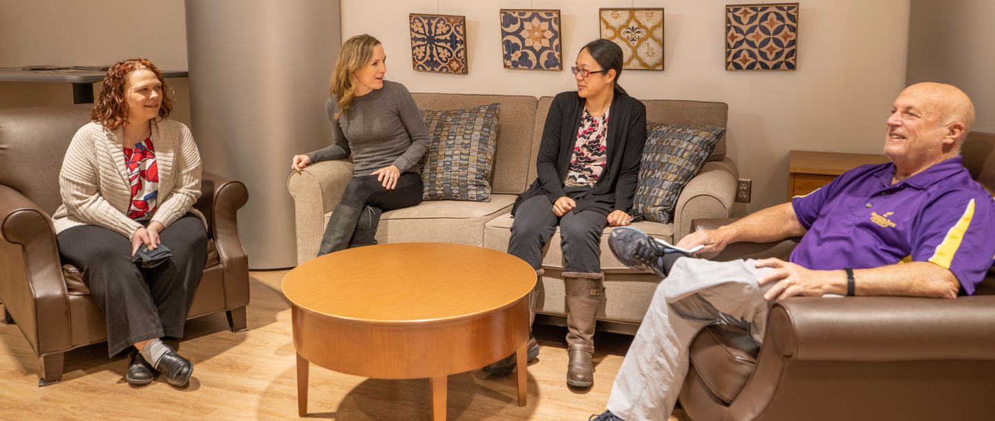 Four staff members sitting and talking together in a lobby area