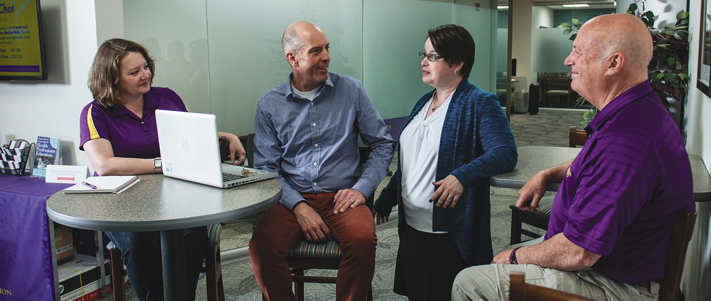 Four faculty members having a discussion in the office hall