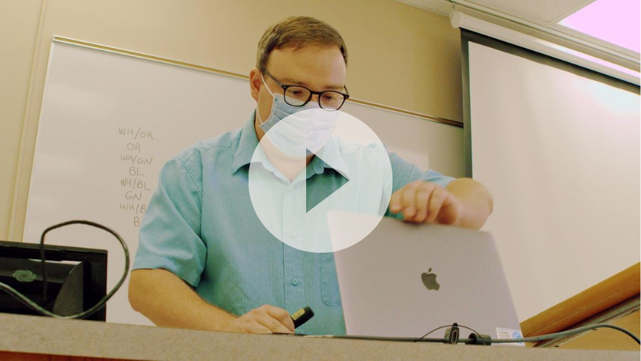 a person wearing a mask and using a laptop