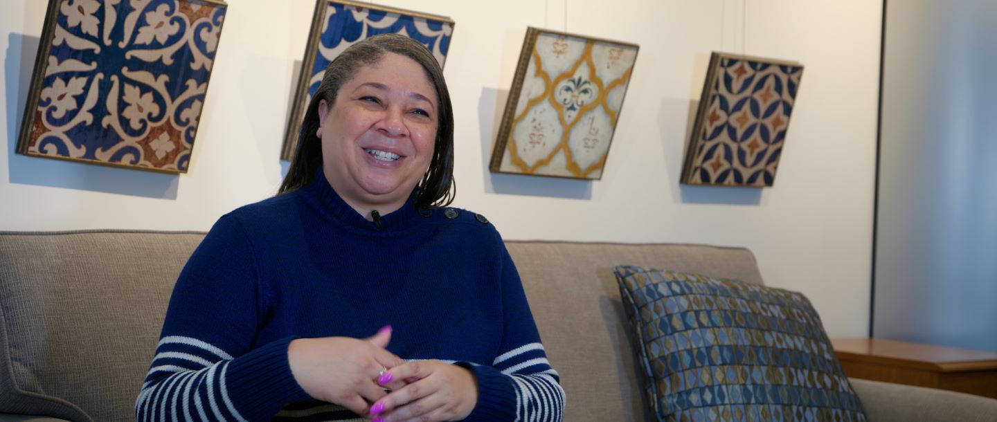 A faculty member sitting on a sofa and smiling