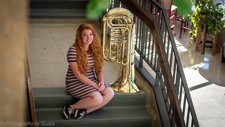 a person sitting on stairs with a tuba statue