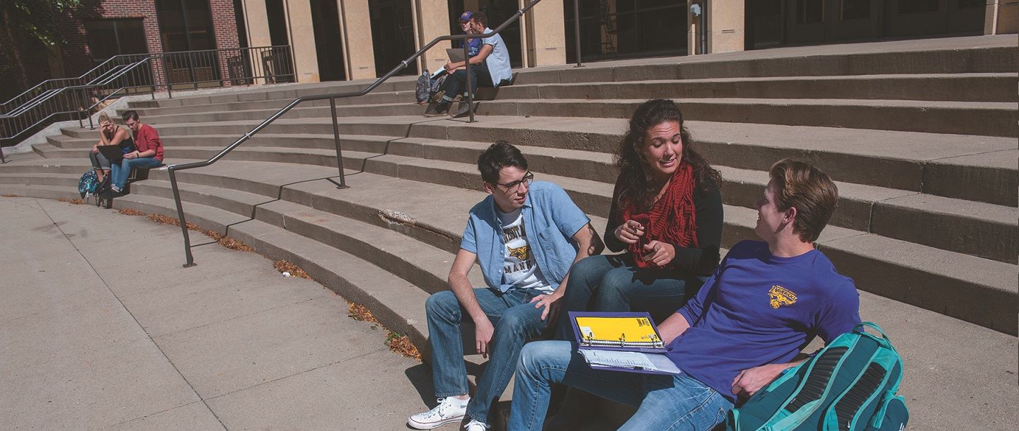 students sitting on a staircase infront of the university theatre