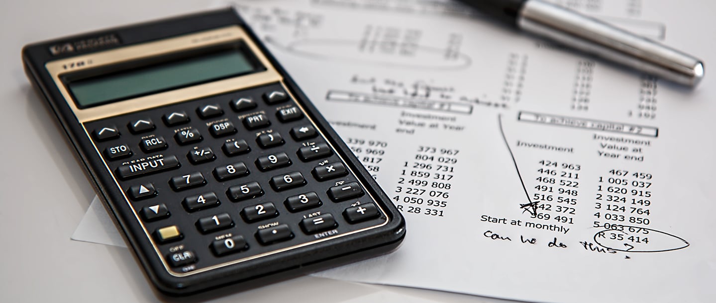 Stock photo of an investment document, calculator and pen on a desk