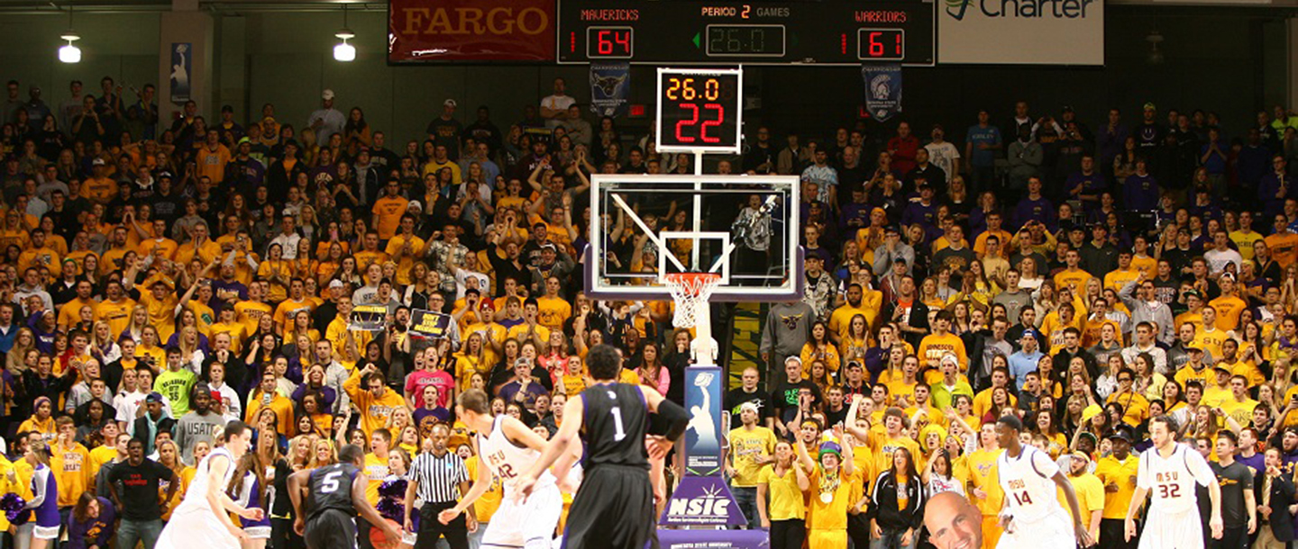 Players running down the court towards the hoop during a basketball game at the Bresnan Arena