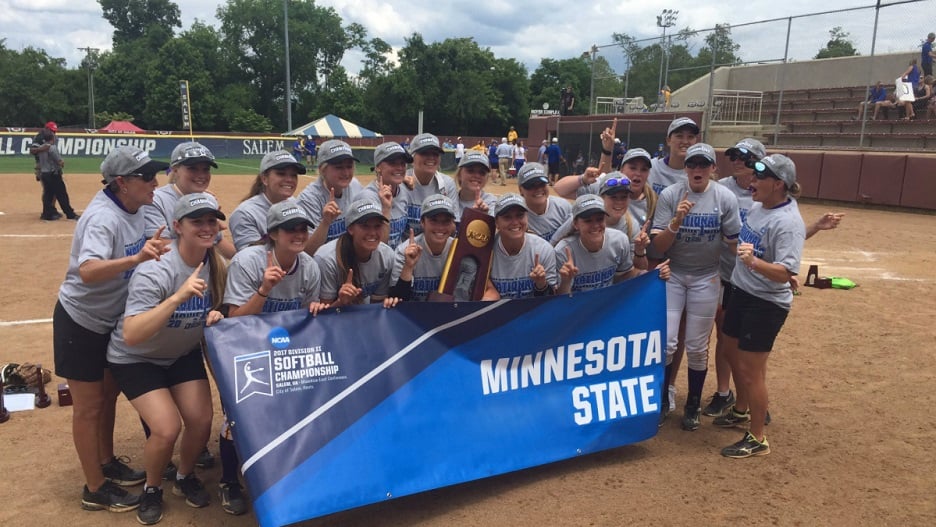 Maverick women's softball team posing on field with trophy at the NCAA Championship