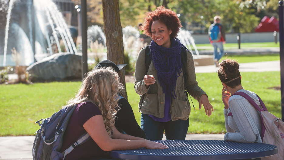 Picture of 3 students sitting next to the University Fountain