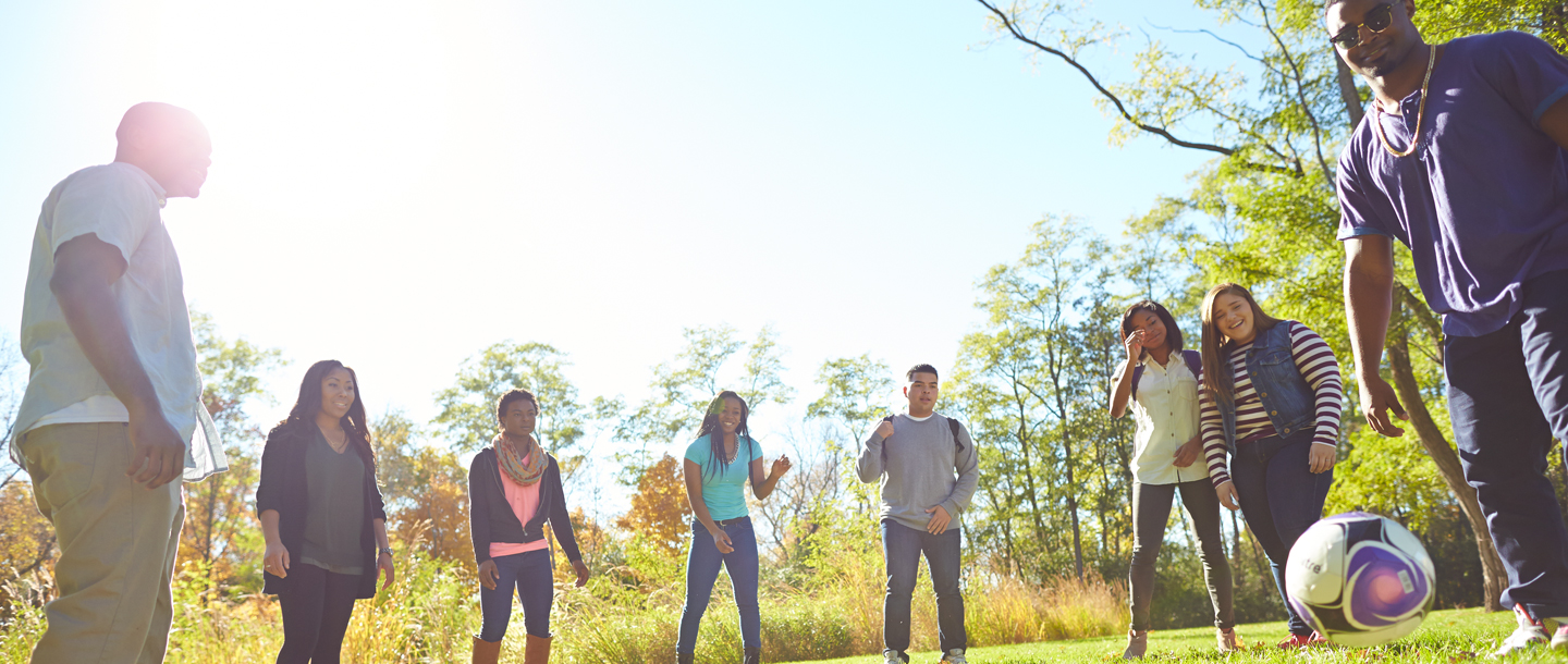 A group of students playing outside on campus with a soccer ball