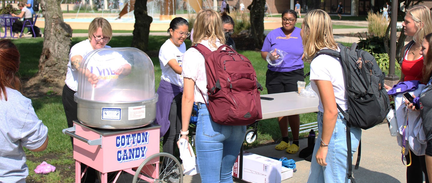 Facutly and staff serving cotton candy to students at an outdoor event