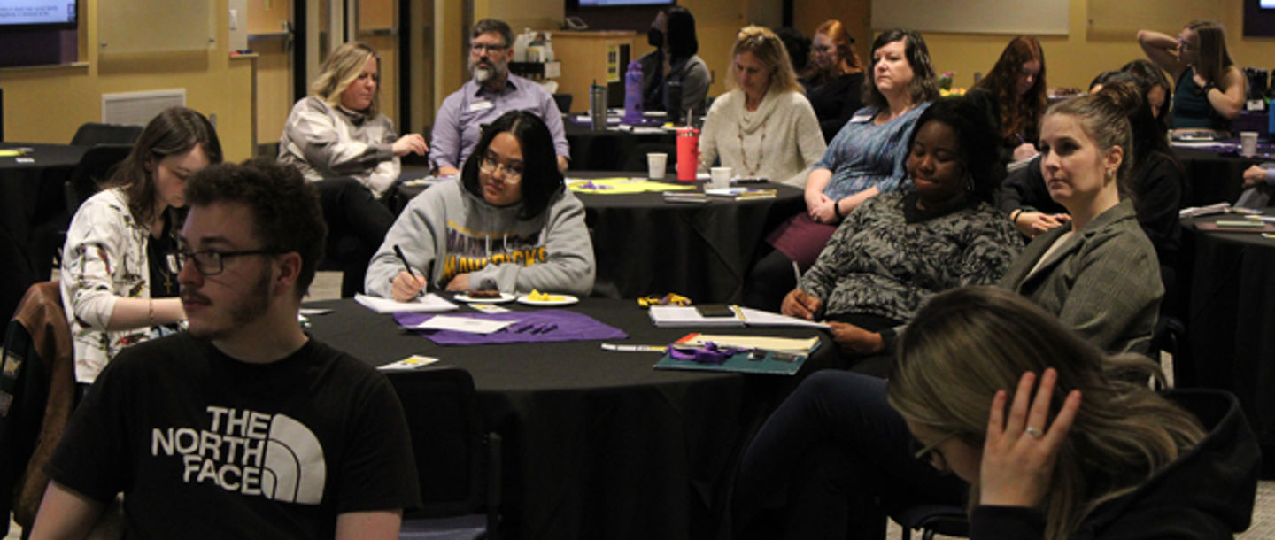 A group of faculty and staff sitting in at tables during a training session