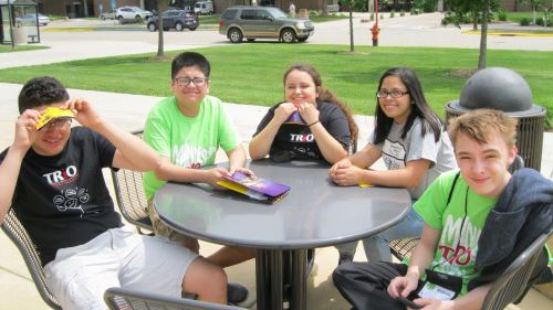Five students posing around a table outside on campus