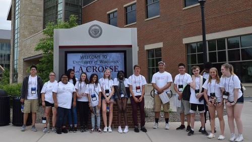 A group of Educational Talent Search students posing in front of the welcome sign outside of the University of Wisconsin La Crosse campus entrance