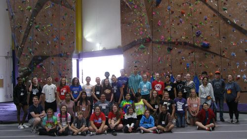 A large group of junior high students at myer's field infront of rock climbing wall