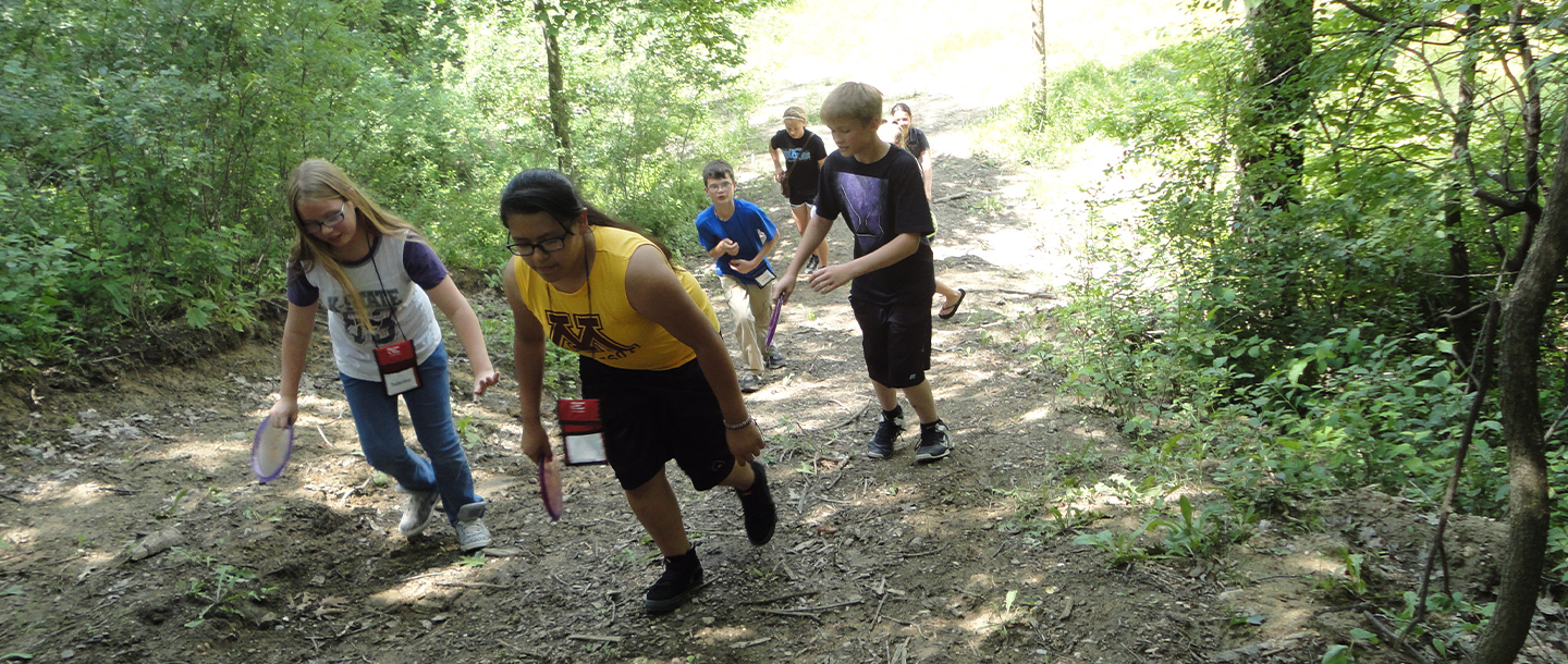 ETS students walking up a hill while playing frisbee golf