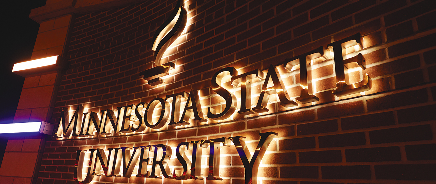 Minnesota State University, Mankato logo in front of the CSU building glowing in the dark