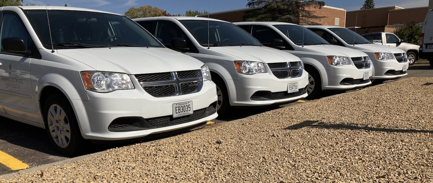 Fleet of white vans parked in a row in the parking lot