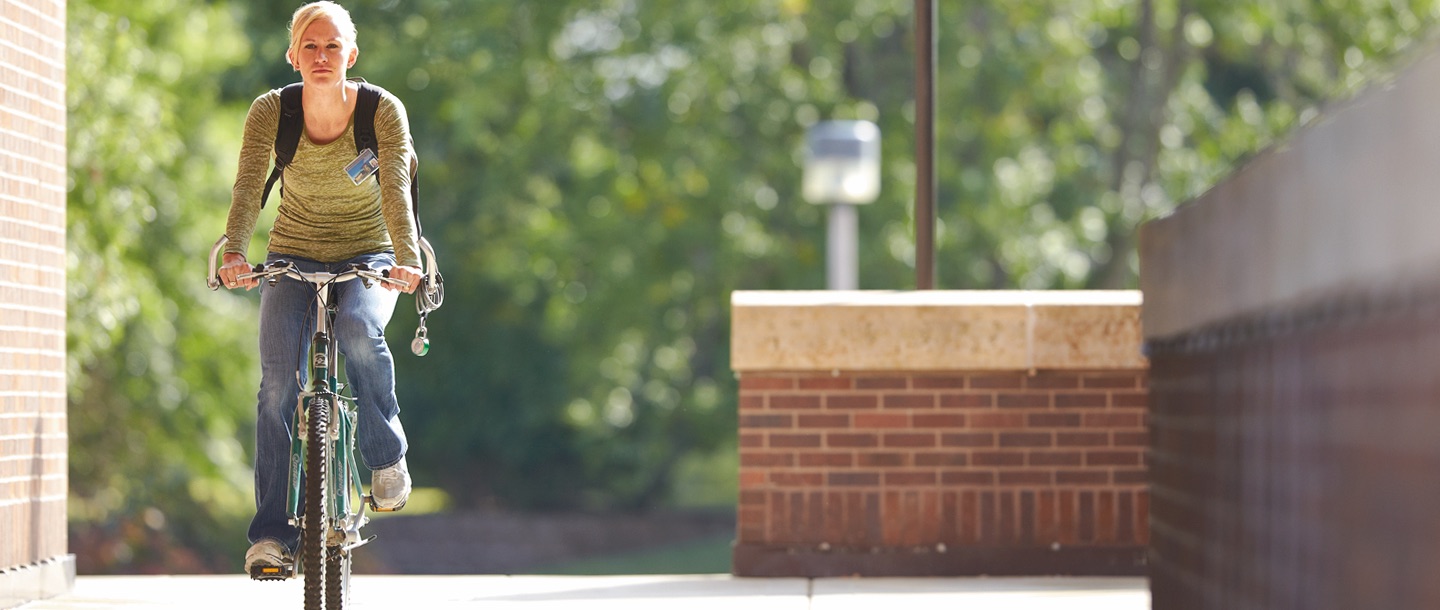 a girl bicycling by the Trafton science center corridor