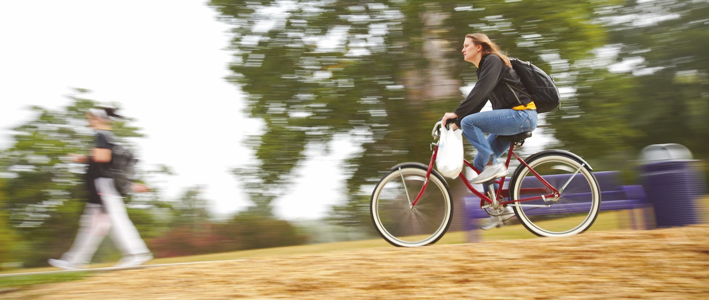 Girl bicycling on campus by the Bell Tower