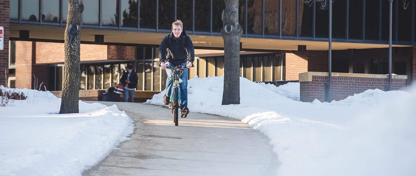 Student bicycling during the winter by Trafton Science Center