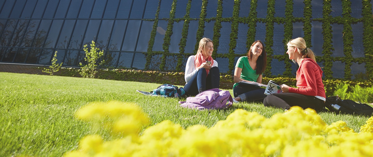 students sitting in grass by highland north