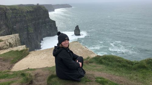 Isabella Taylor in Dublin, Ireland on the hillside overlooking the cliffs and ocean on a cloudy day